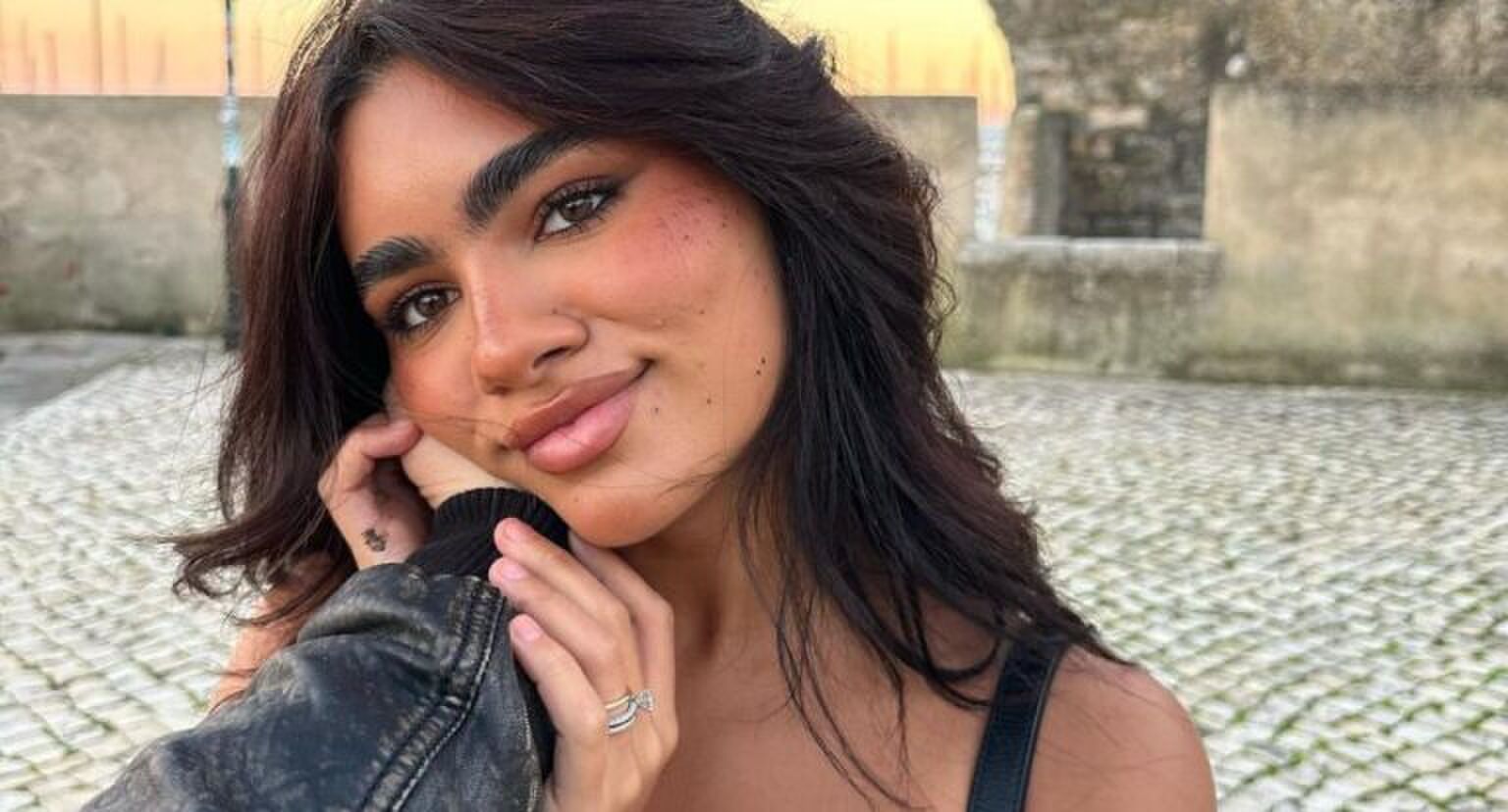 Een jonge vrouw kijkt liefdevol de camera in.