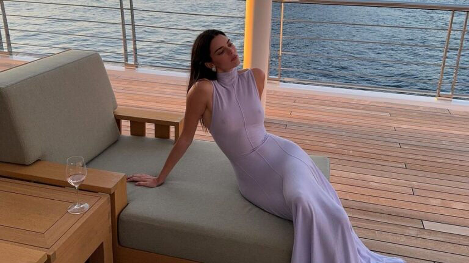 Kendall Jenner in een paarse jurk ligt op een bank.