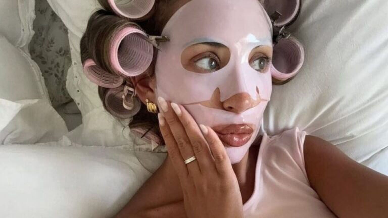 Meisje ligt met gezichtsmaskertje op in bed.