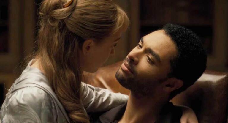 Een vrouw zit op schoot bij een man en ze kijken elkaar aan.