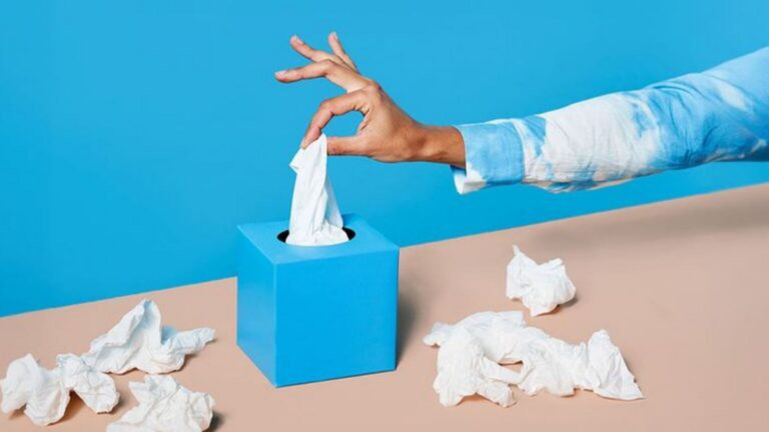 Een hand die een tissue pakt.