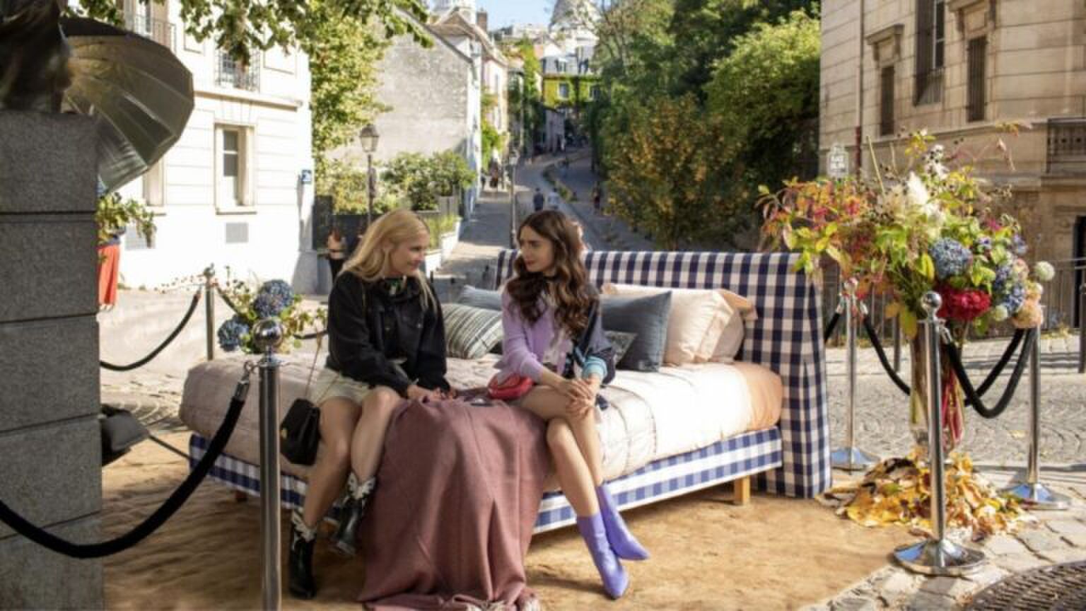 Emily uit Emily in Paris zit op een bed.