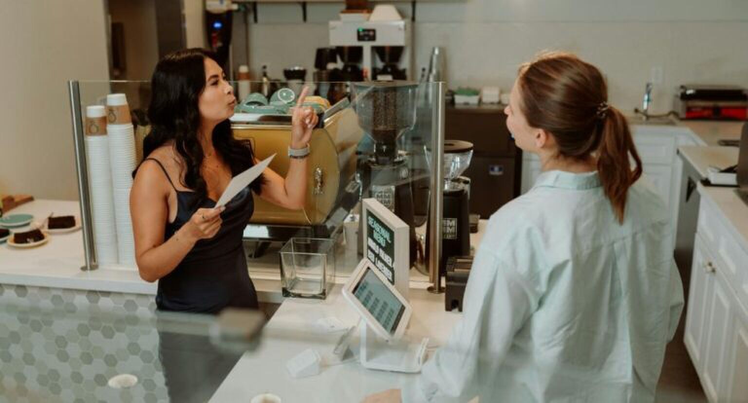 Een koffiezaak waar een jonge vrouw een drankje bestelt aan de toonbank.