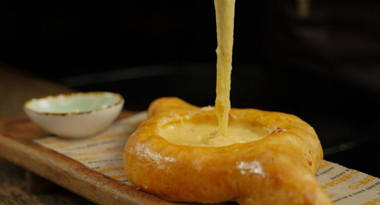 Iemand die een stukje van een kaas-knoflookbrood pakt.