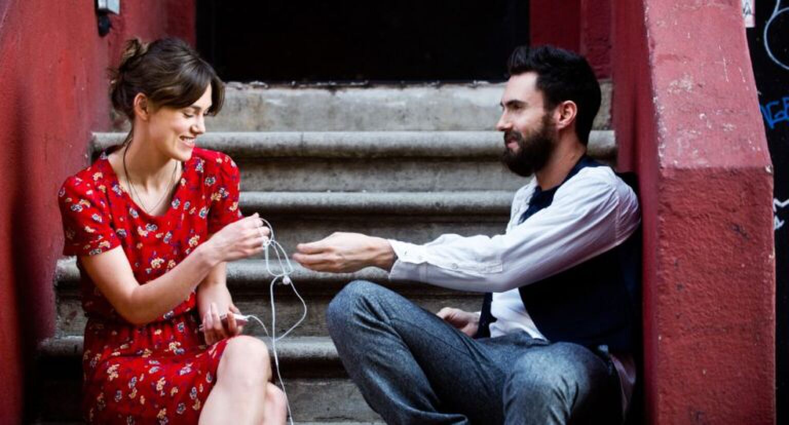 Twee mensen op een trap die samen muziek luisteren.