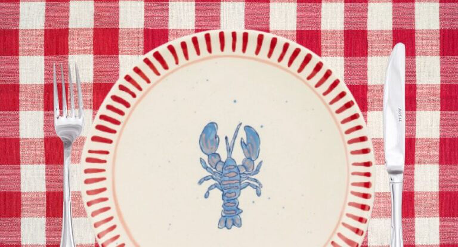 Een tafel met een geruit tafelkleed en een kreeft-bord van Karwei.