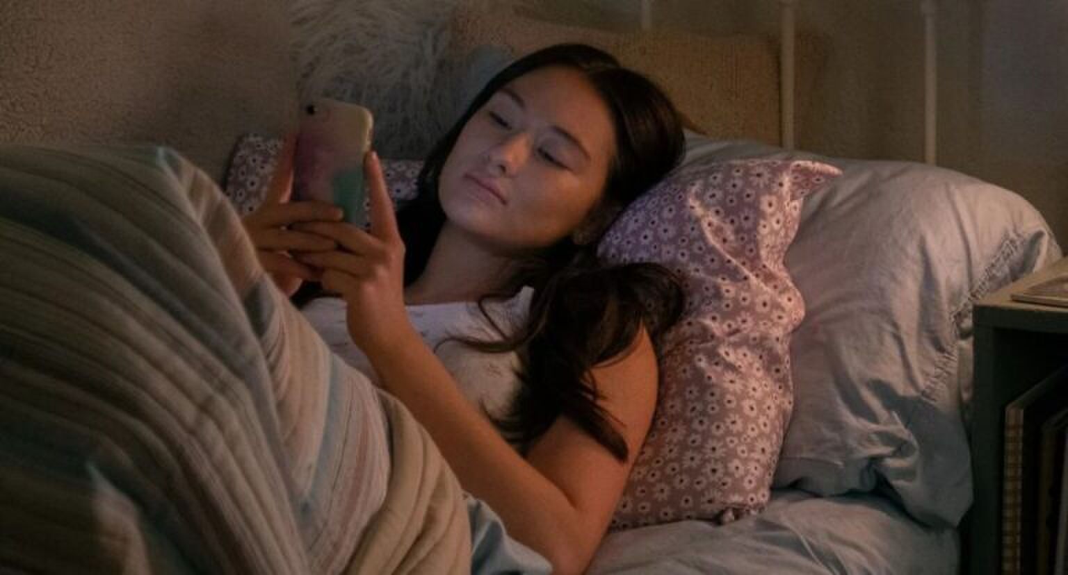 meisje ligt in bed op haar telefoon