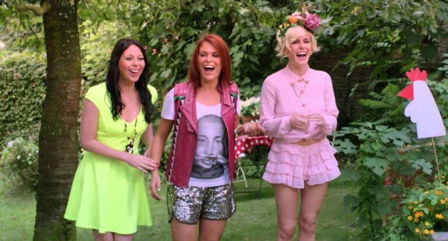 Sc&egrave;ne uit K3 Dierenhotel waarin Kristel, Karen en Josje op een rijtje staan in een tuin.