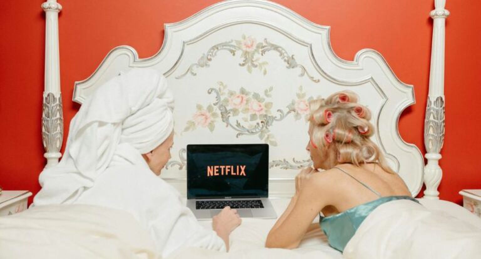Twee vrouwen die op bed liggen en Netflix kijken.