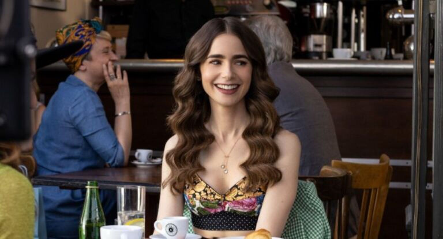 Emily van Emily in Paris zit op een terrasje met haar haren in de krul.