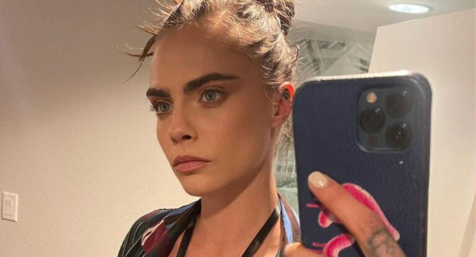 Vrouw met wilde wenkbrauwen neemt een spiegelselfie.