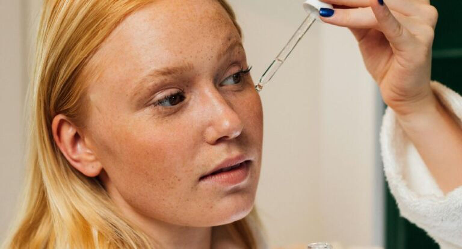 Een vrouw die serum op haar gezicht aanbrengt.