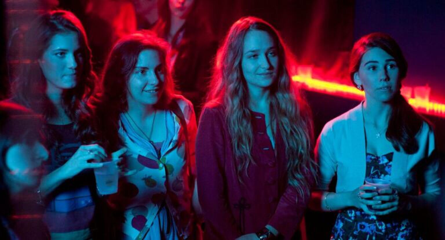 Vier meiden die in neon-lichten op een feestje staan.