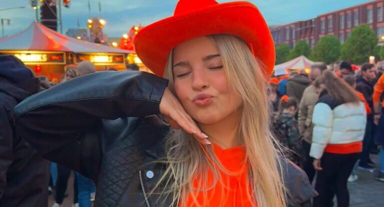 Meisje met een oranje shirt, een oranje cowboyhoed en een leren jasje.