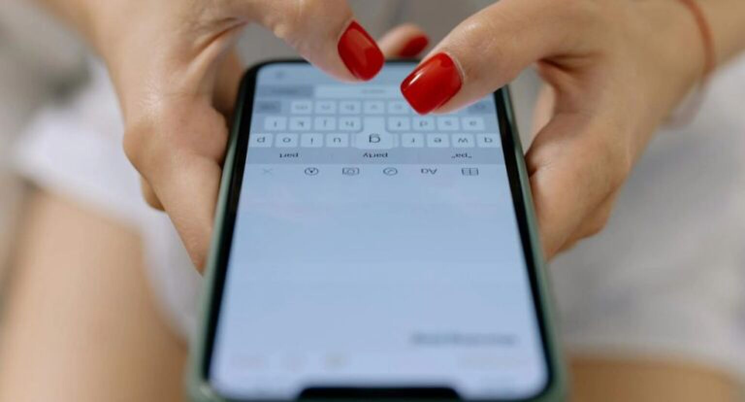 Een hand met rode nagels typt in de Notes app.