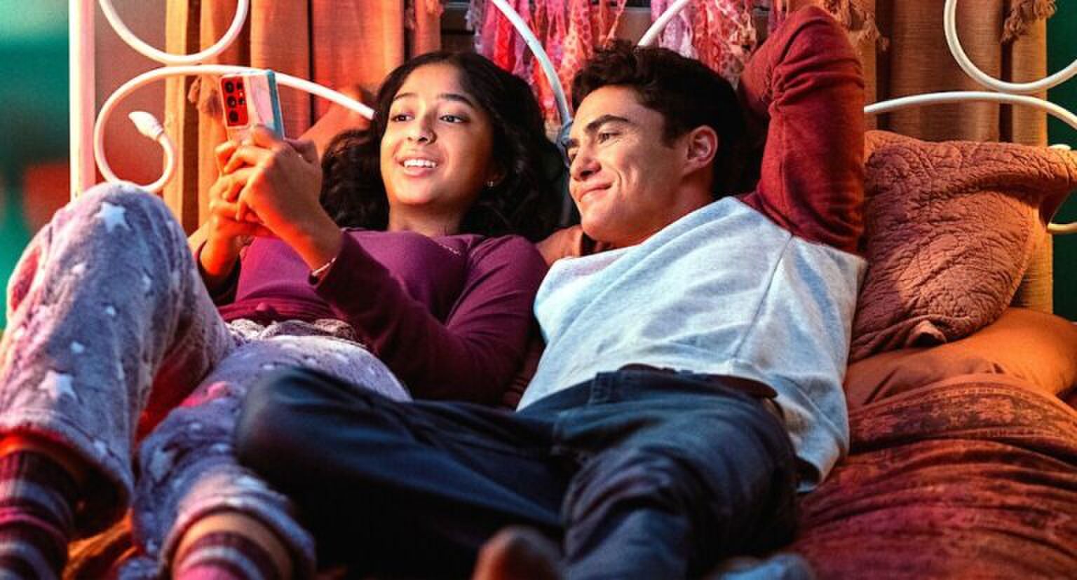 Sc&egrave;ne uit Never Have I Ever waarin Devi en Paxton op bed liggen en naar Devi haar telefoon kijken.