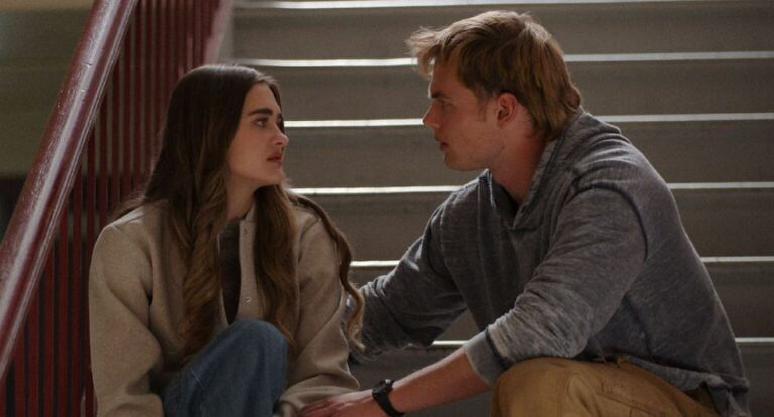 Twee personages uit de serie zitten samen op de trap.