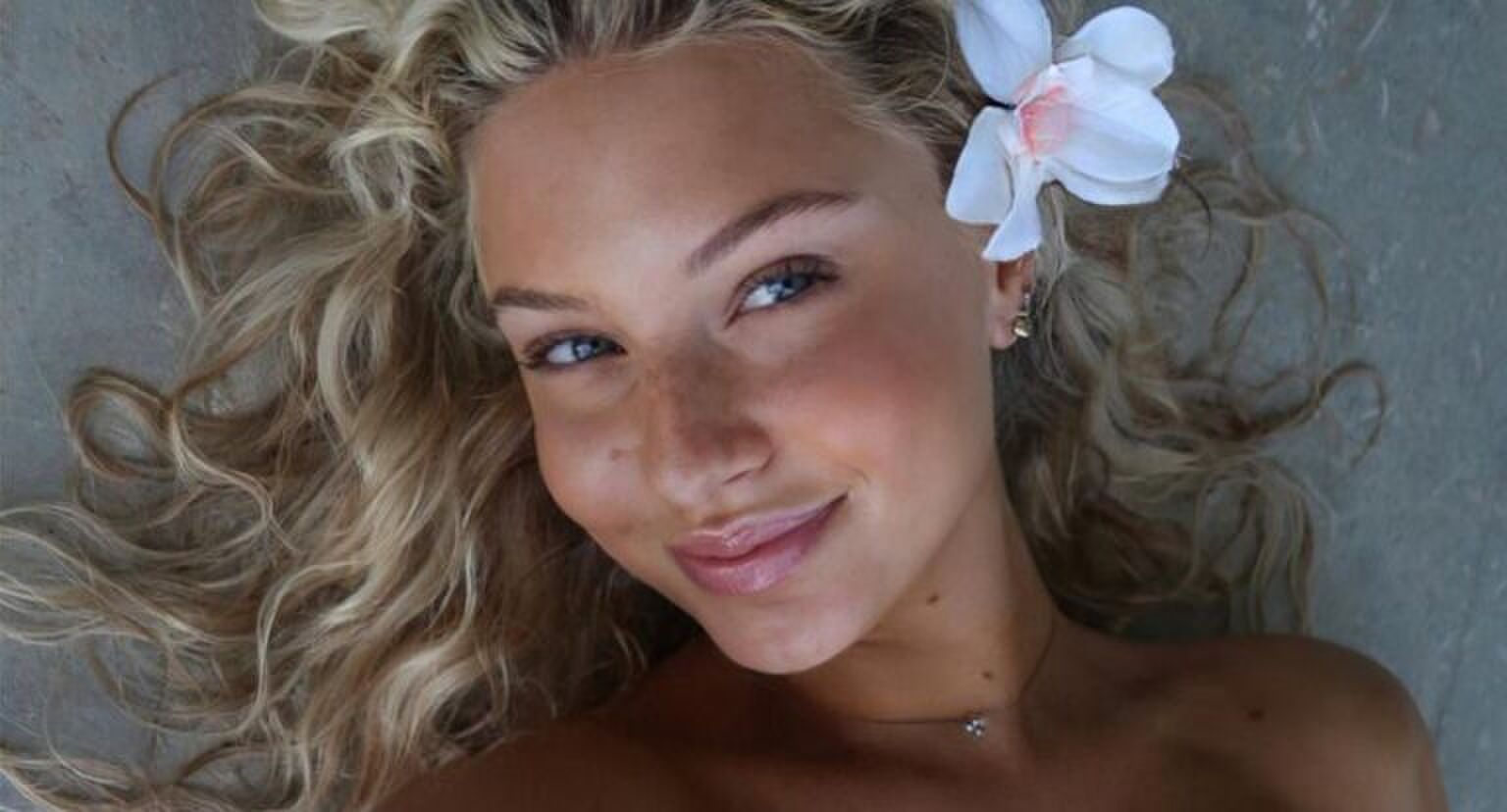 Meisje met een stralende huid en een bloem in haar haar.