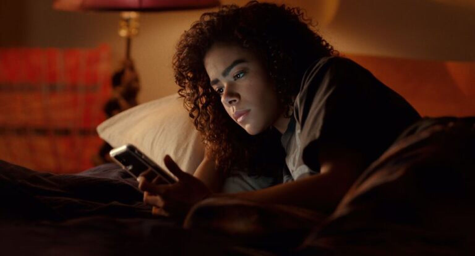 Sc&egrave;ne uit Ginny & Georgia waar Ginny in bed ligt en op haar telefoon kijkt.