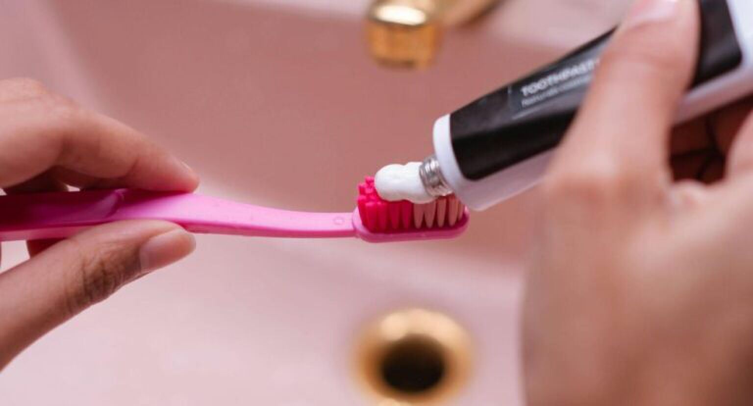 Een roze wasbak en een roze tandenborstel met tandpasta.