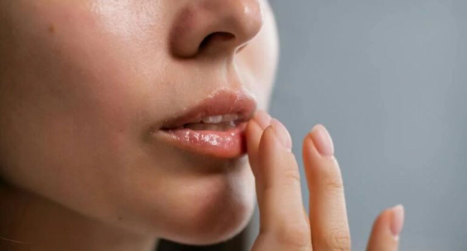 Vrouw doet lippenbalsem op haar lippen met haar hand.