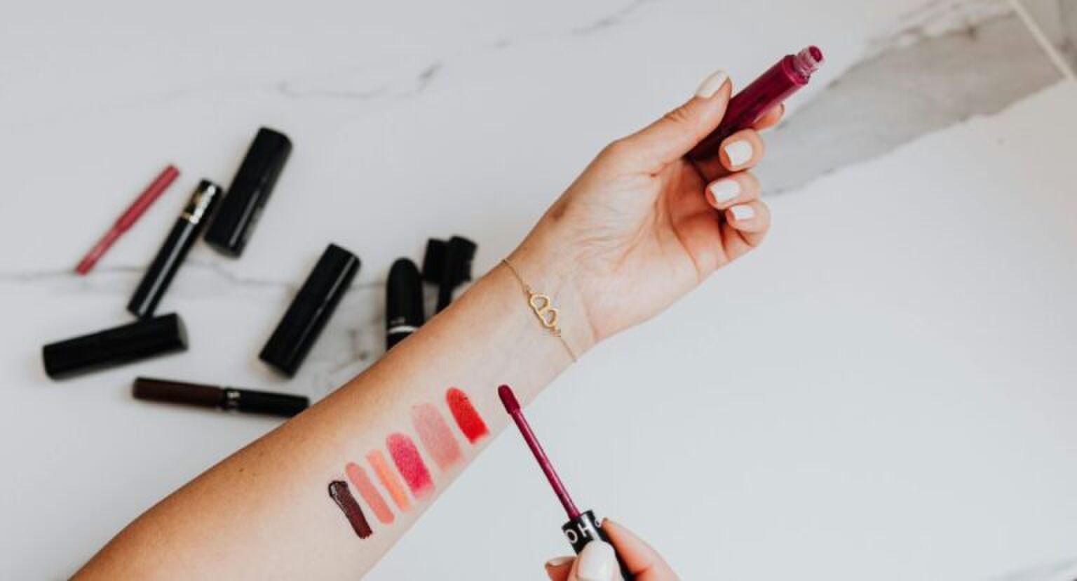 Een vrouw met verschillende kleuren lippenstift op haar arm uitgeprobeerd.