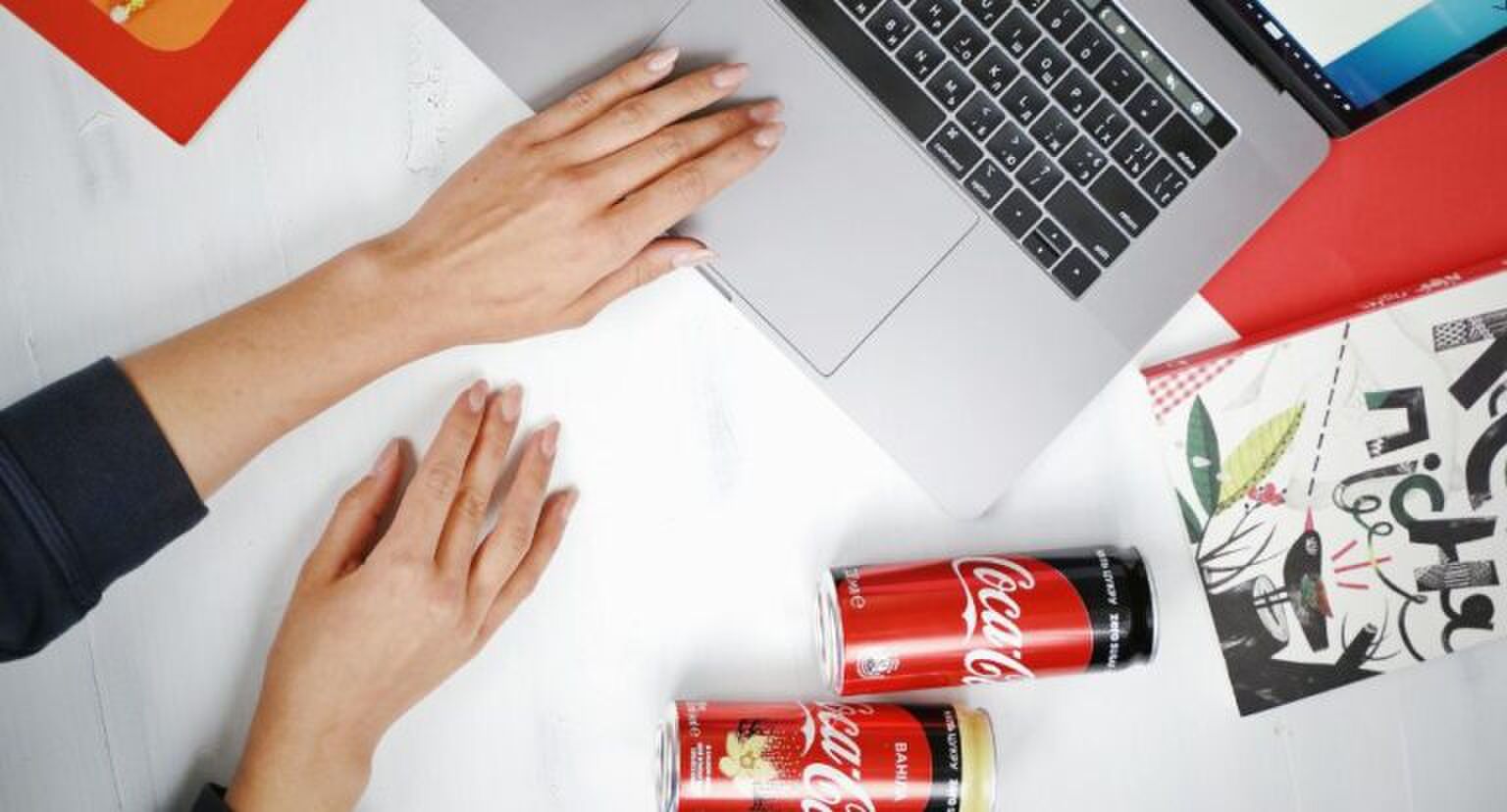 Twee blikjes Cola Zero liggen een bureau.