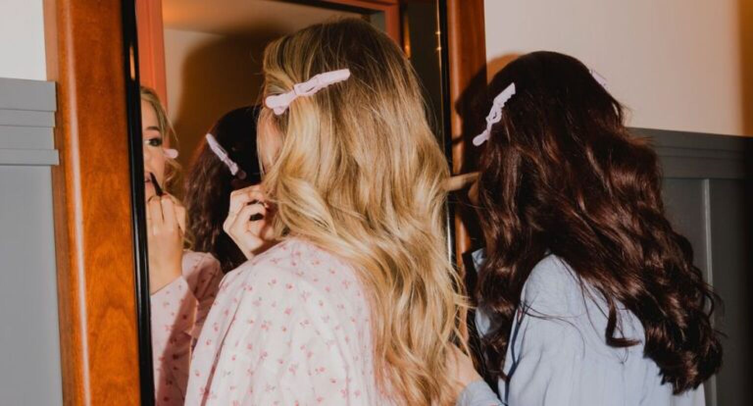 Twee vrouwen doen voor de spiegel hun make-up.