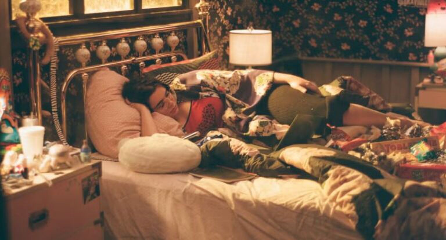 Meisje ligt in bed en kijkt een serie.