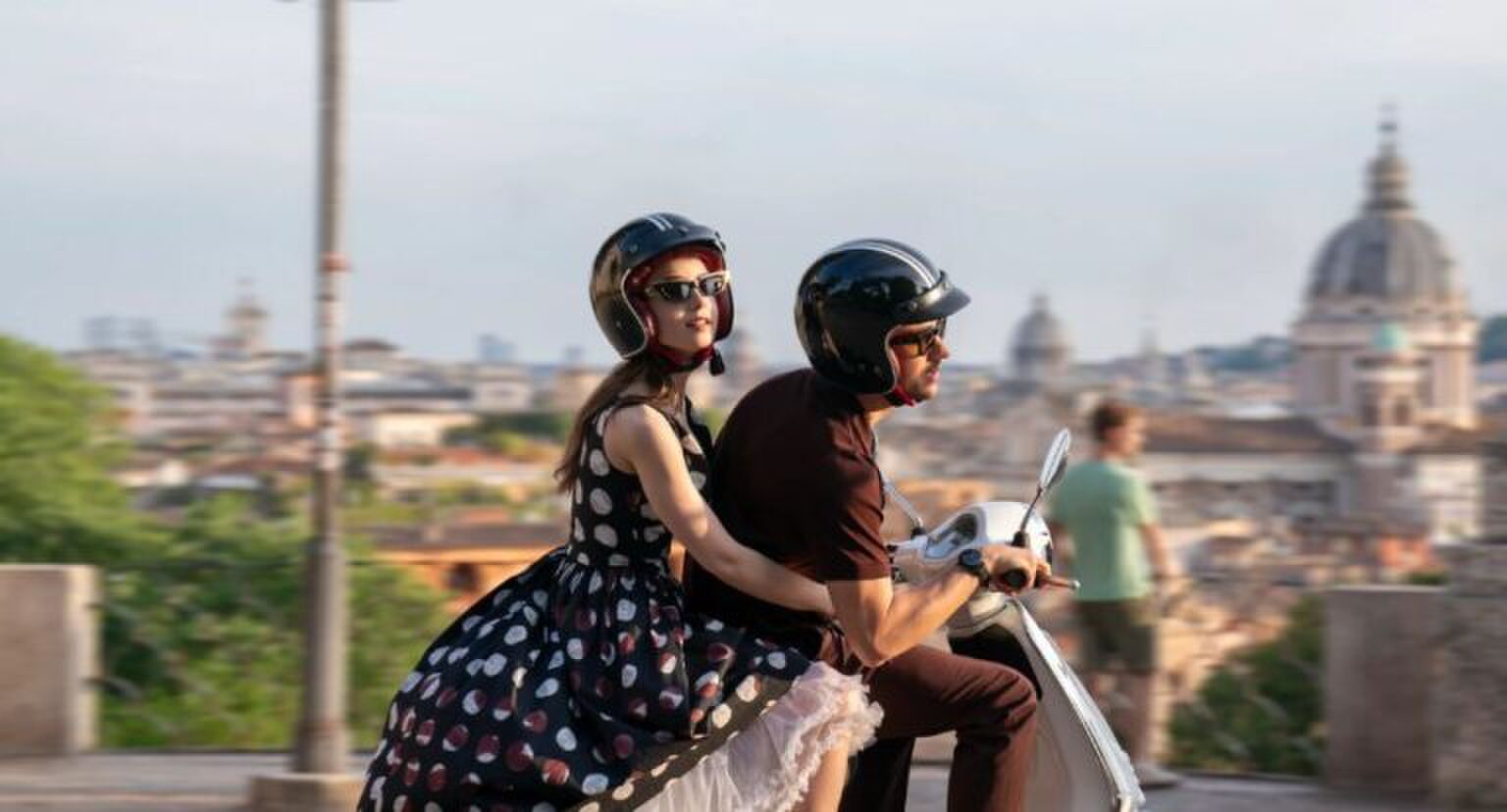 Sc&egrave;ne uit Emily in Paris waar Emily achterop de scooter bij Marcello zit.