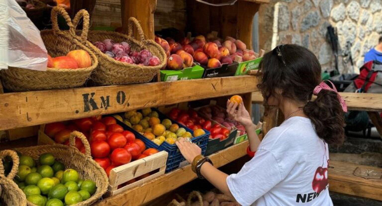 Een meisje die bij een fruitmarkt fruit uitkiest.