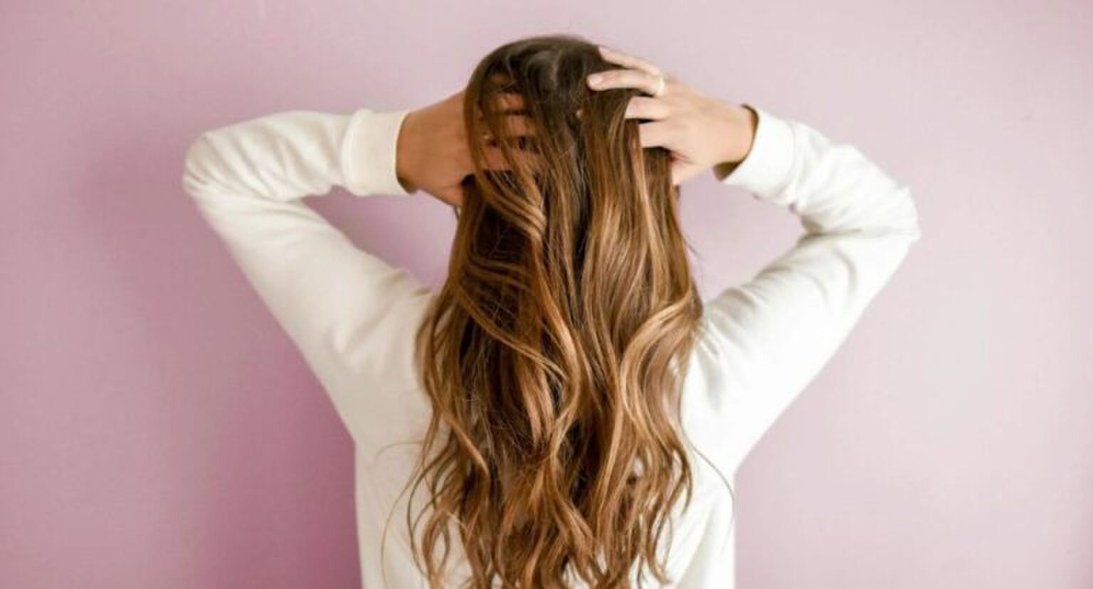 Vrouw gaat door haar haar met haar handen.