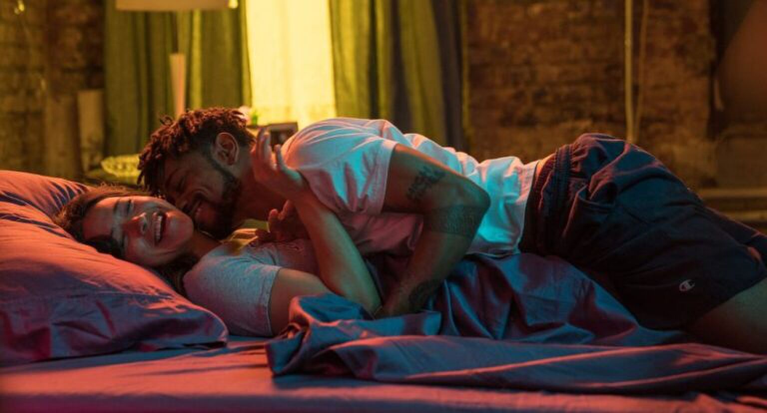 Man en vrouw liggen samen lachend in bed.