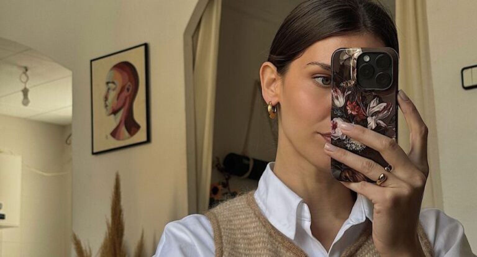 Een vrouw die een spiegelselfie maakt en naked nails heeft.