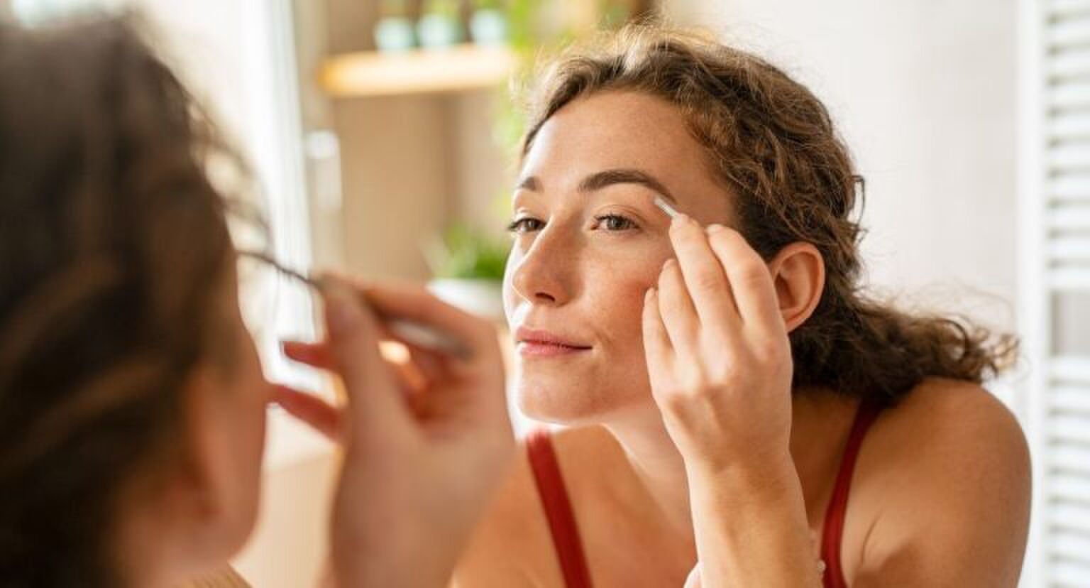 Een vrouw die haar wenkbrauwen aan het epileren is.
