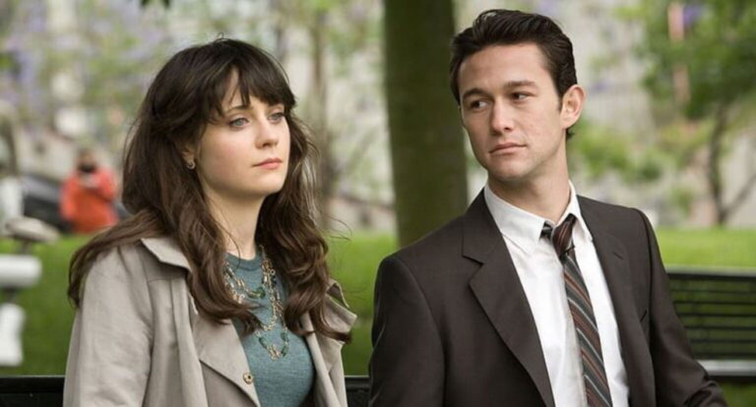 Meisje en jongen zitten naast elkaar, terwijl het meisje voor zich uit staart, kijkt de jongen naar haar.