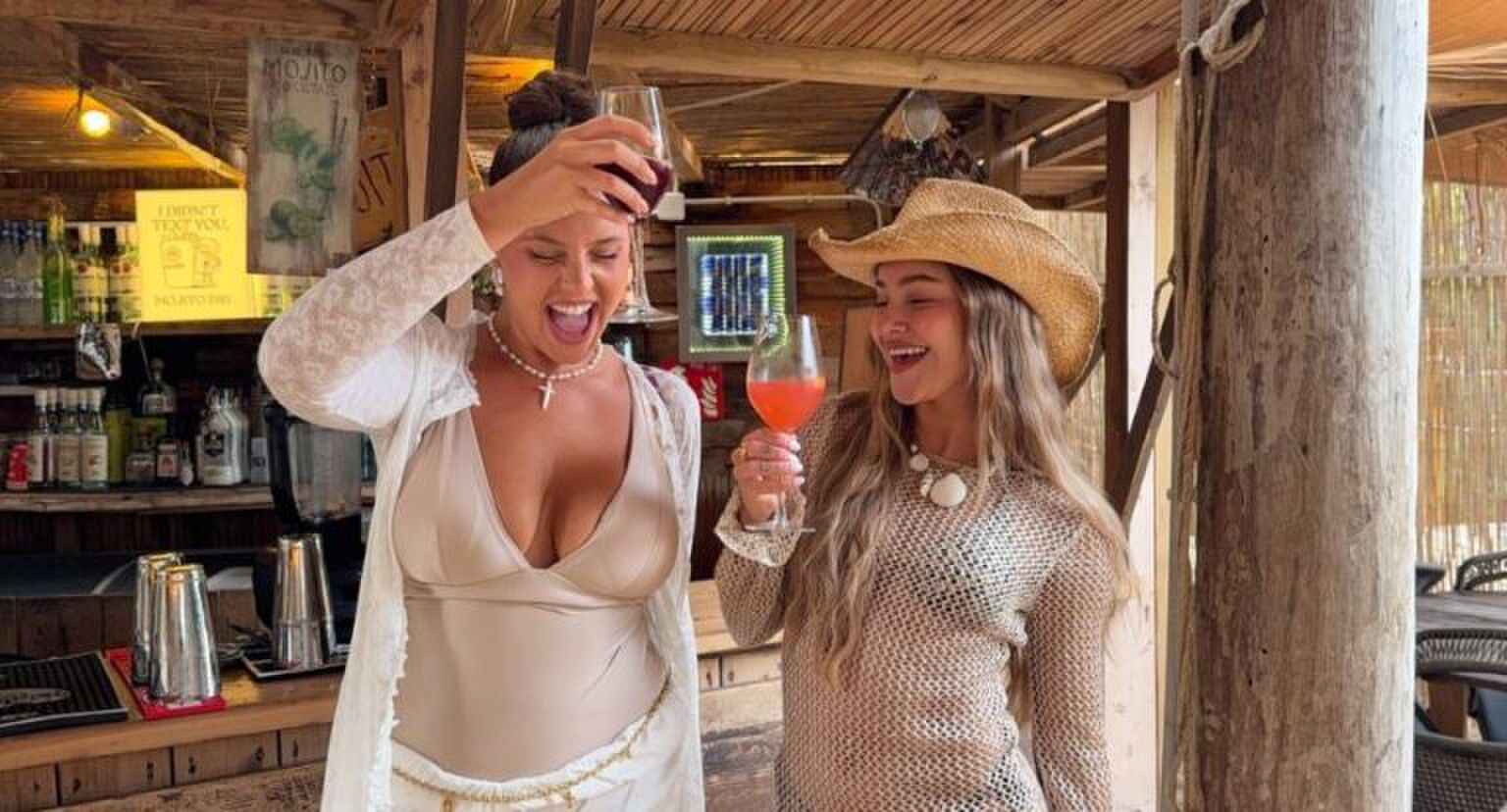 Twee meiden die blij hun drankjes in de lucht houden.