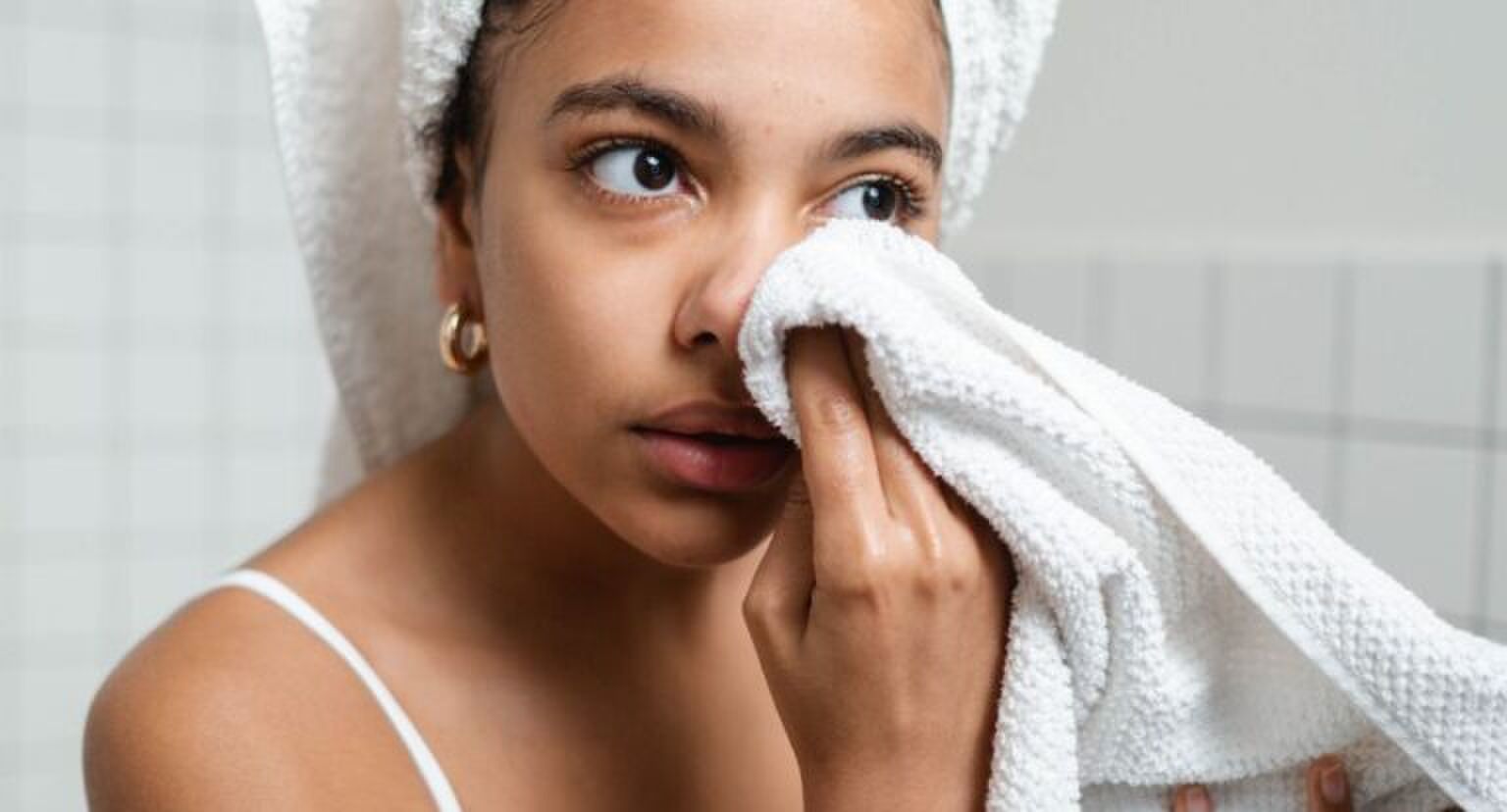 Een vrouw met een handdoek in de badkamer.