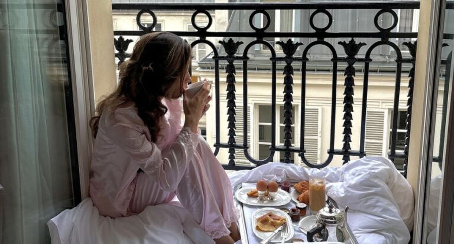 Een jonge vrouw zit in haar pyjama in het raamkozijn.