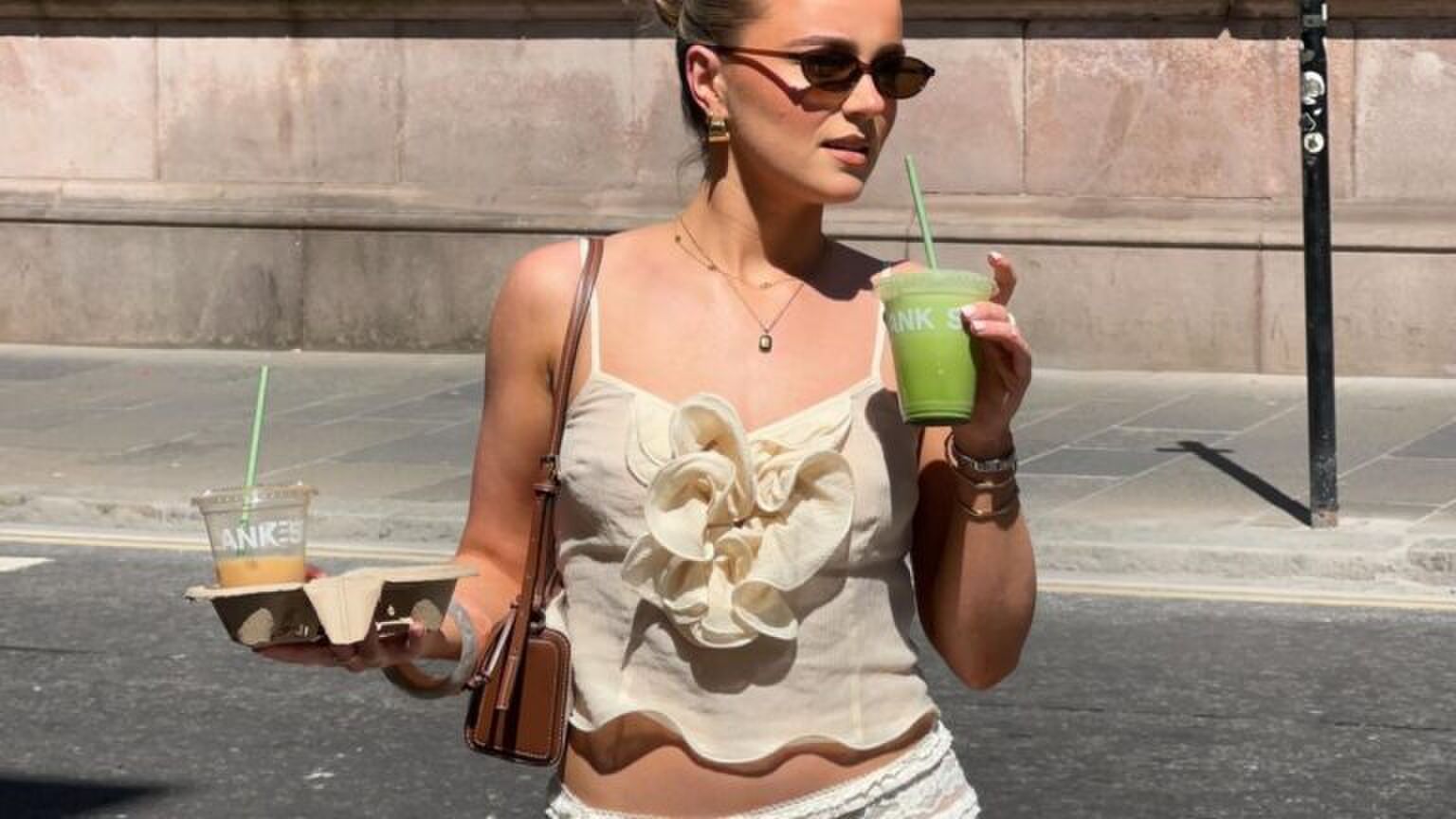 Een jonge vrouw loopt over straat met matcha in haar hand.