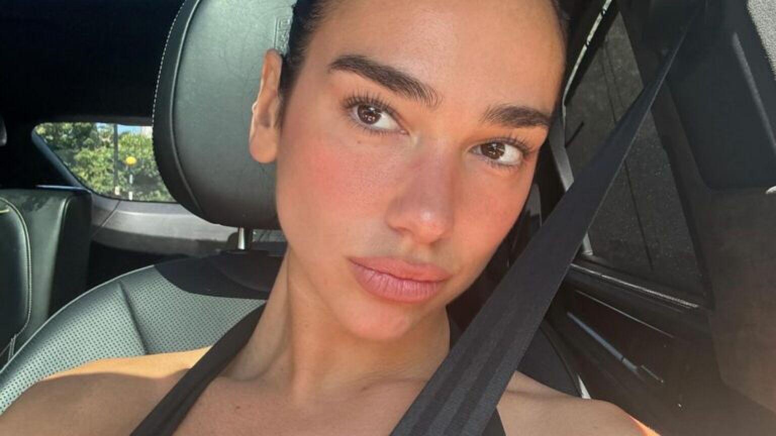 Dua Lipa zit in haar Porsche.