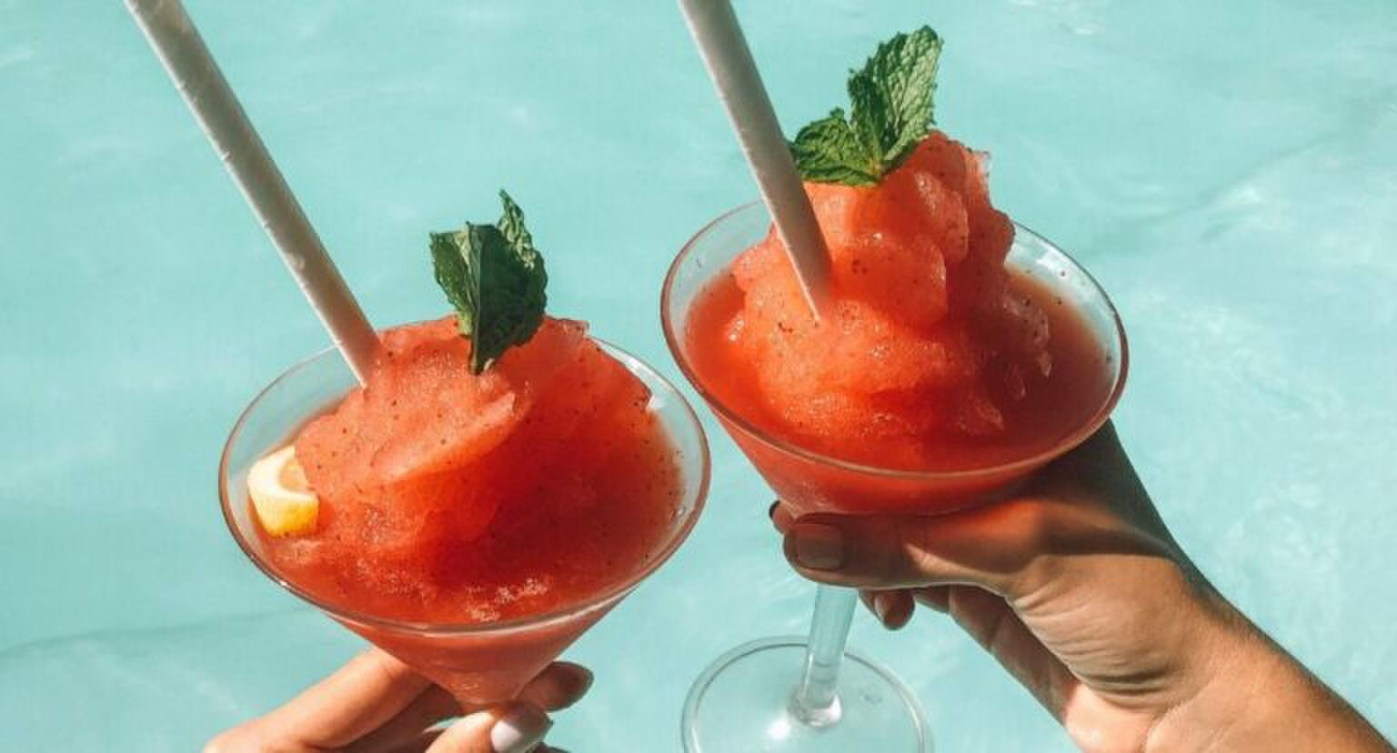 Twee frozen cocktails naast elkaar boven een zwembad.