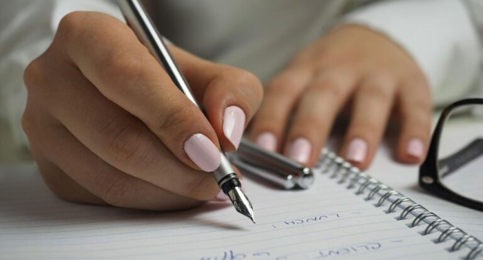 Vrouw schrijft op papier met pen.