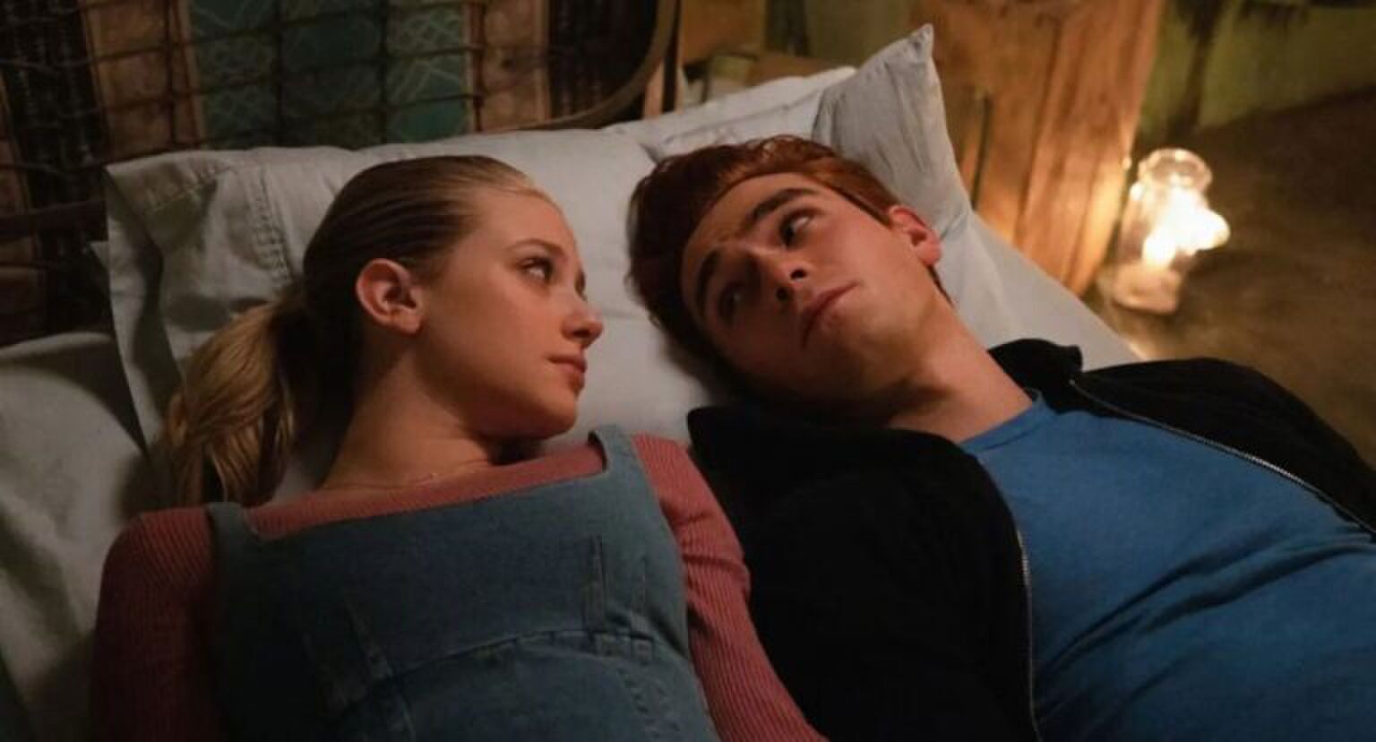 Jongen en meisje liggen op bed en kijken elkaar aan.