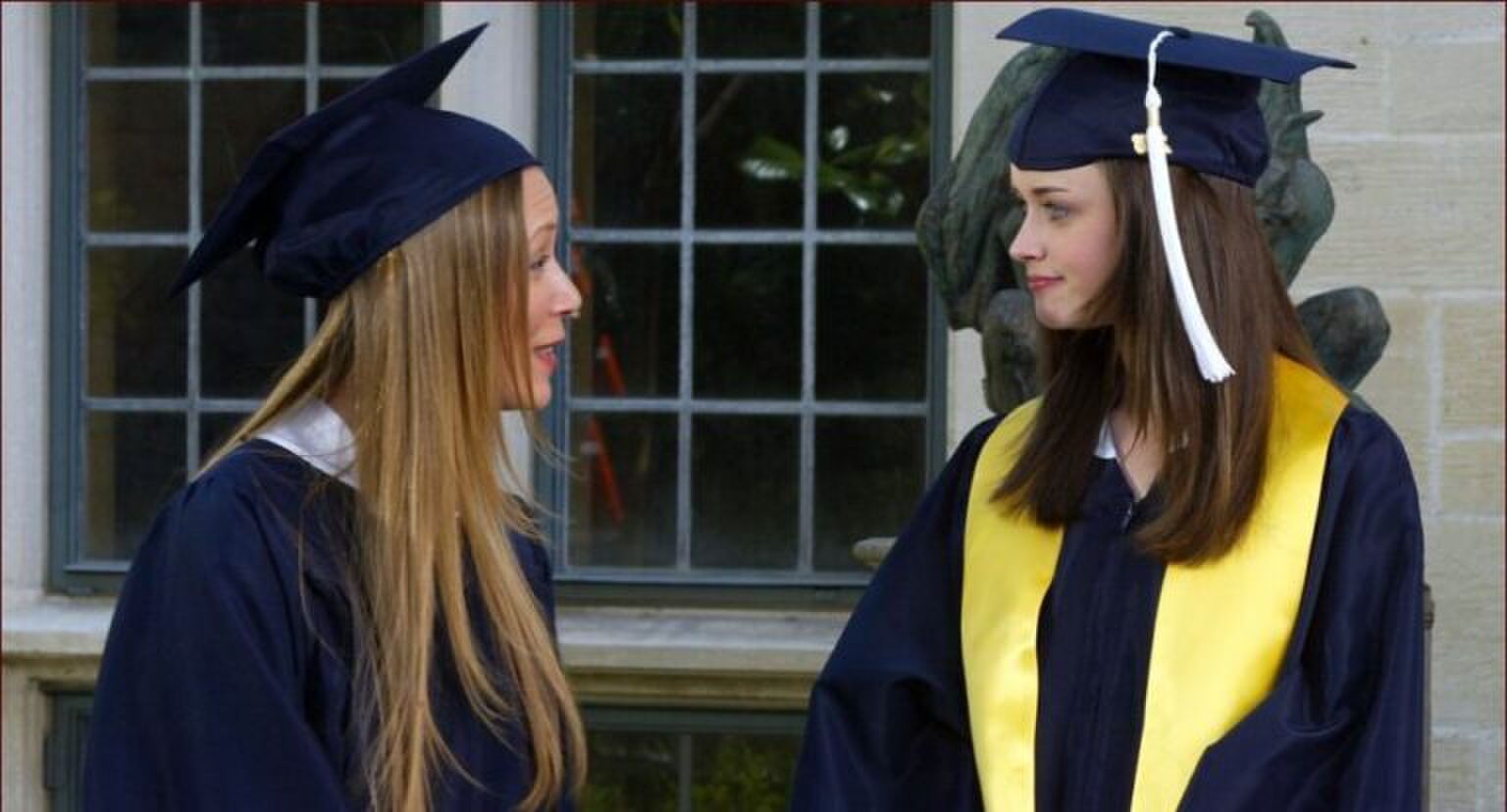 Twee vrouwen in cap and gown kijken elkaar aan.