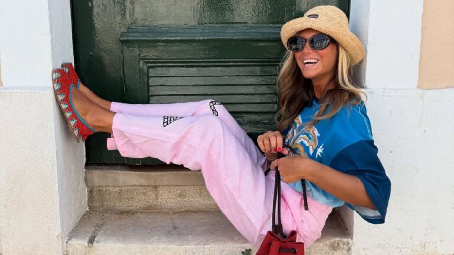 Een vrouw in een kleurrijke outfit die in een deuropening zit.