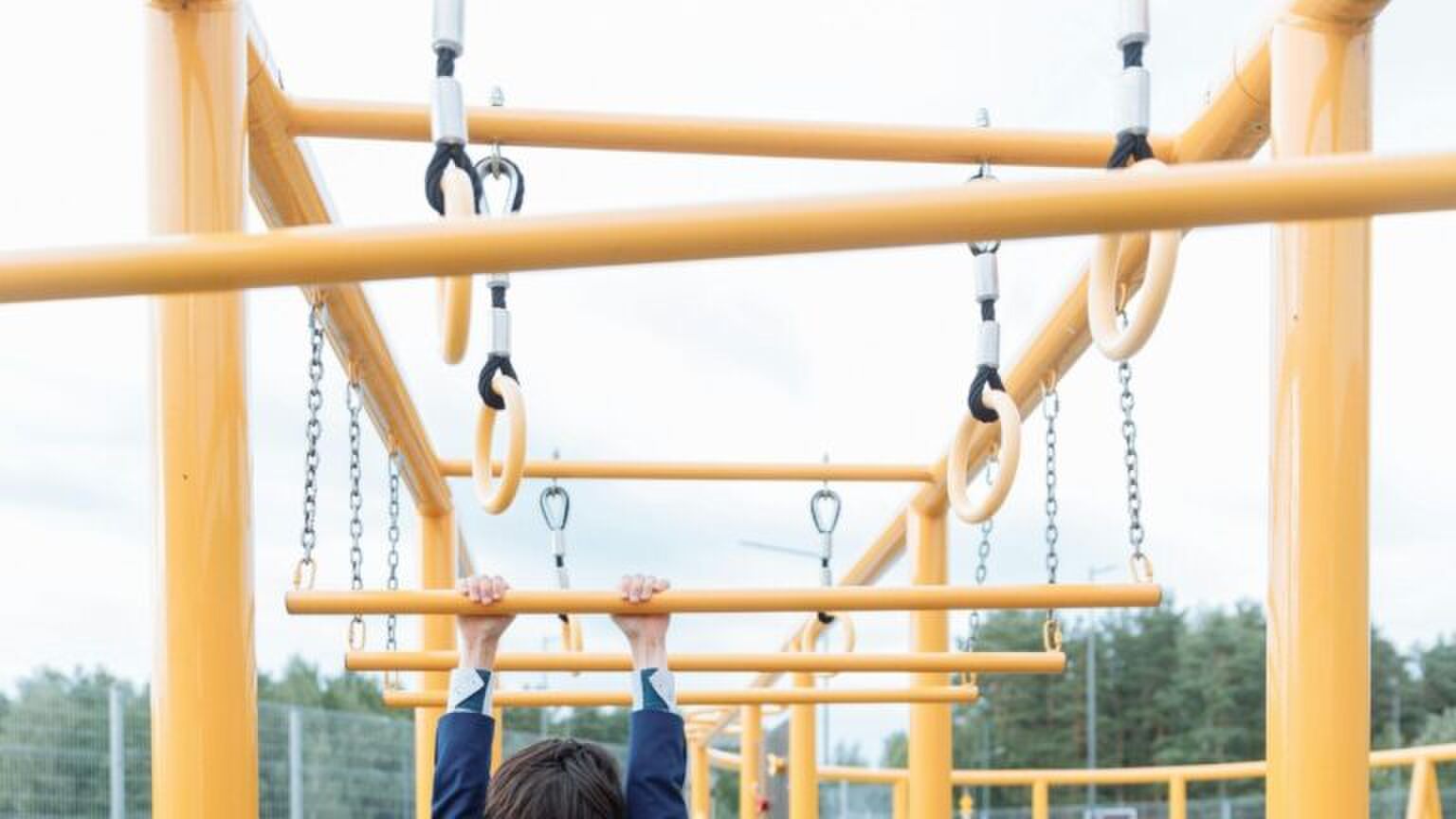 Een kind hangt aan een klimrek.