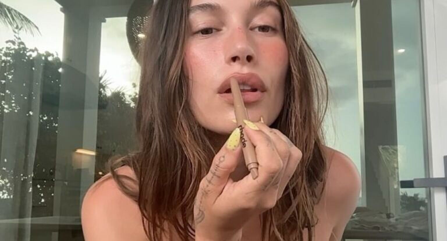 Vrouw doet een bruin-roze liptint op haar lippen.