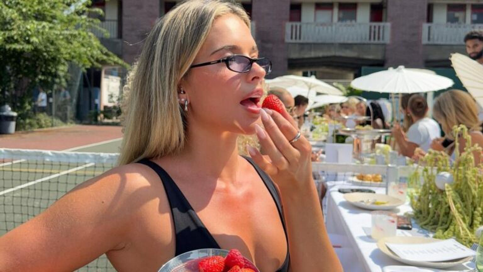 Een meisje met rouge op eet een aardbei.