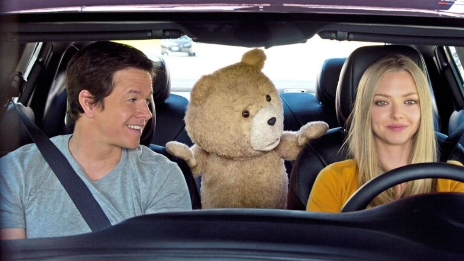 Een vrouw rijdt in de auto, terwijl haar man kijkt.